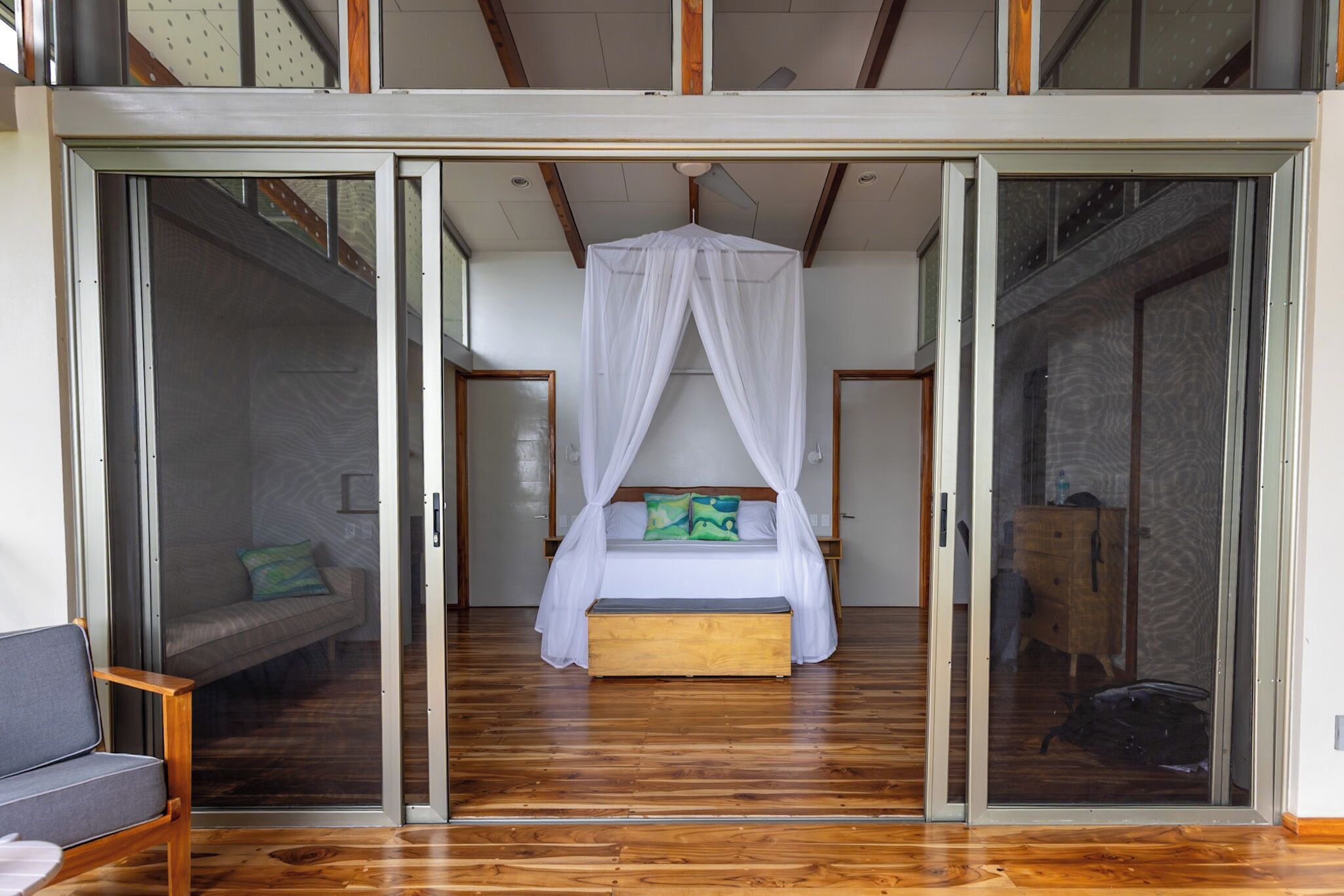A bedroom with a canopy bed, sliding glass doors, and a wooden floor.