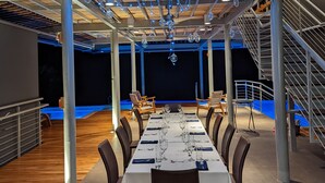 A dining area with a long table set for a meal, surrounded by chairs, and a staircase on one side. - Cielo Lodge (Golfito)