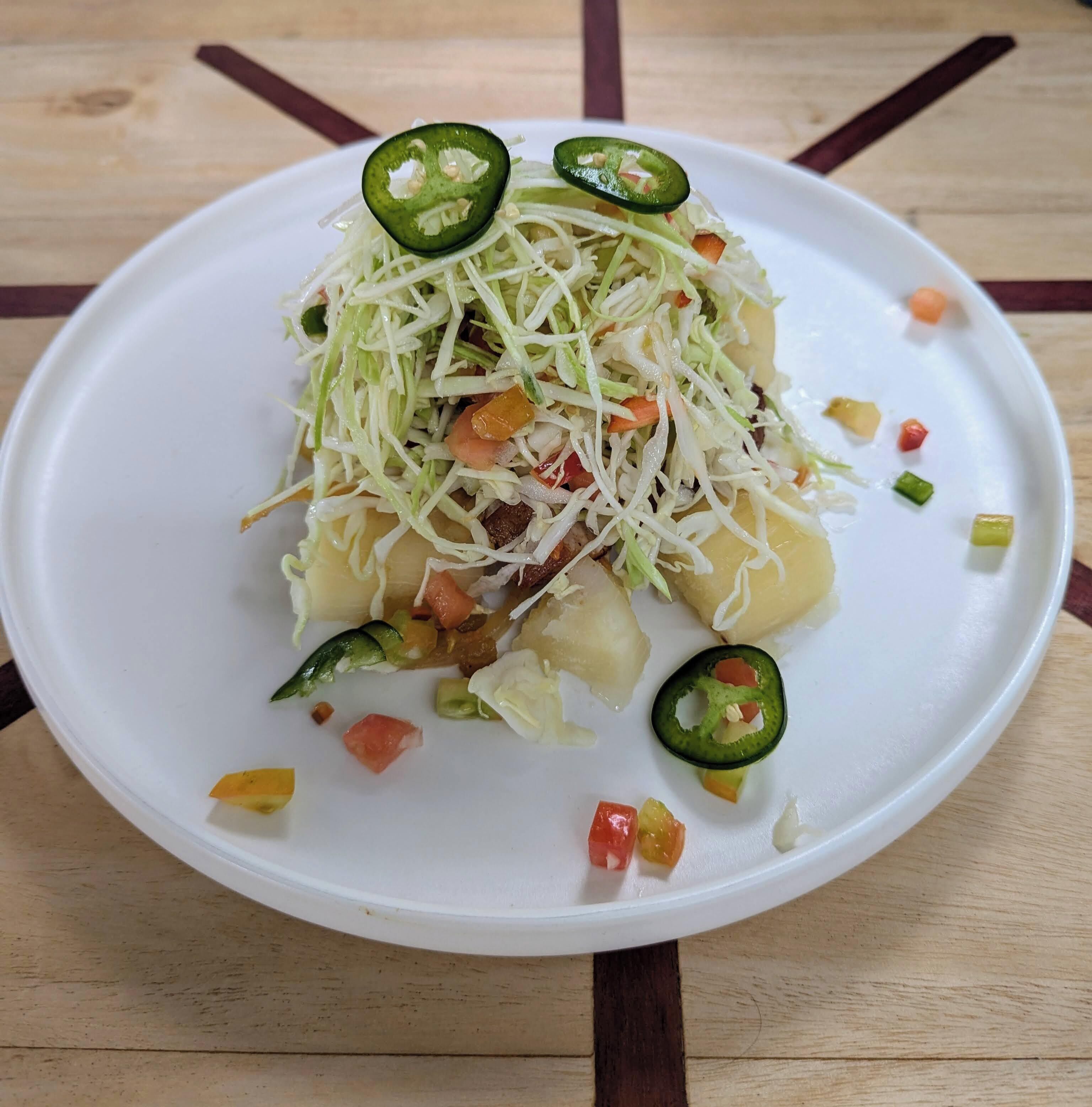 A white plate with a salad on a wooden table.