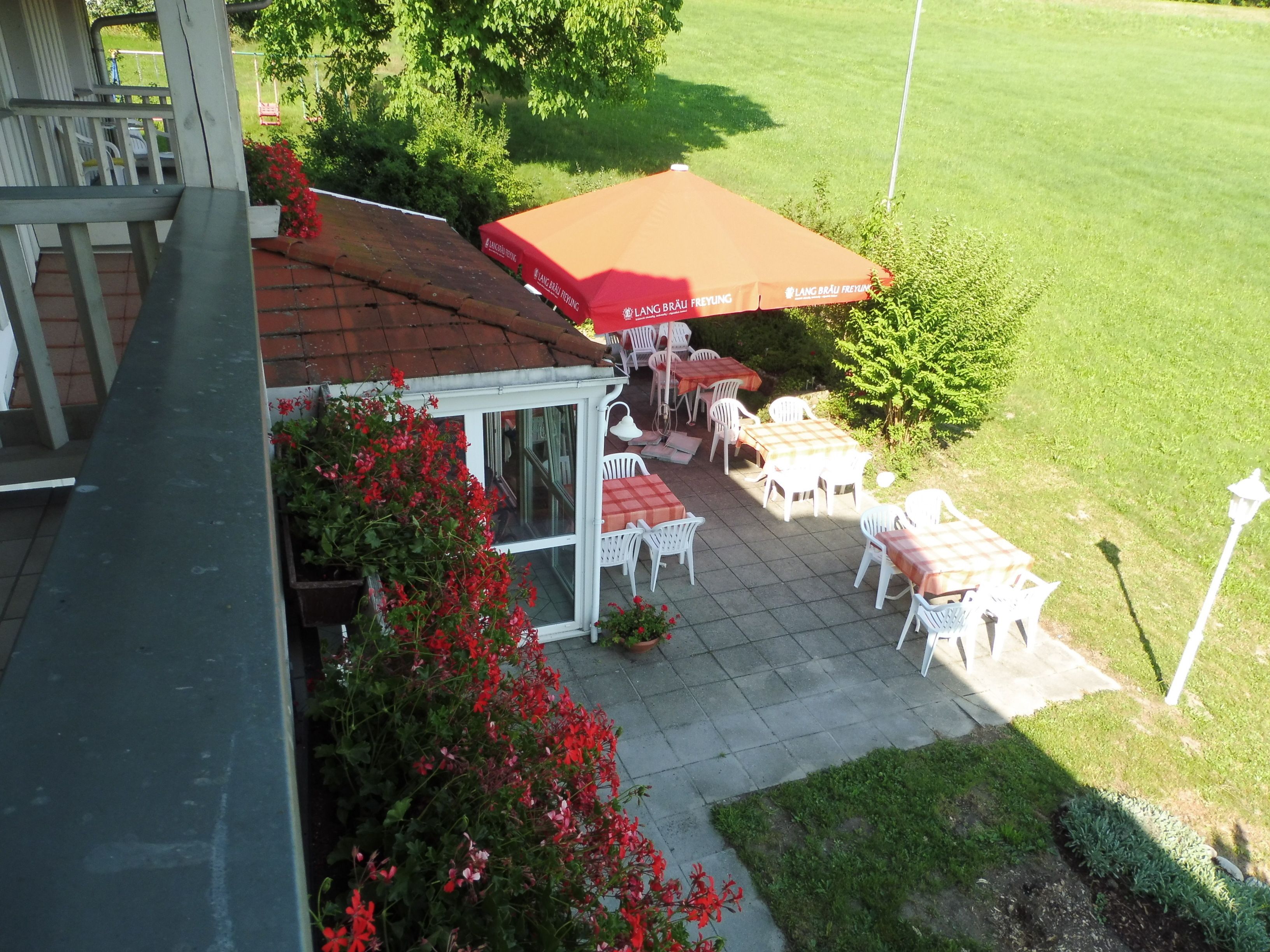 A patio area with outdoor seating, a sheltered table, and a red umbrella.