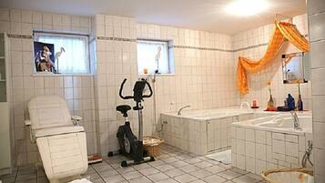 Ein Badezimmer mit weiß gefliestem Boden, einer weißen Badewanne, einer weißen Toilette, einer Duschkabine und einem Fenster mit Vorhang.