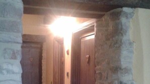 Un couloir étroit aux murs de pierre et aux portes en bois.