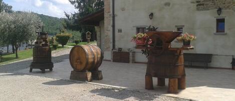Un patio con barriles de madera rústicos, un edificio de piedra y un banco.