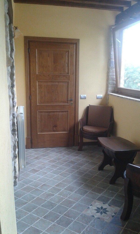 A room with a wooden door, a chair, a table, and a window.