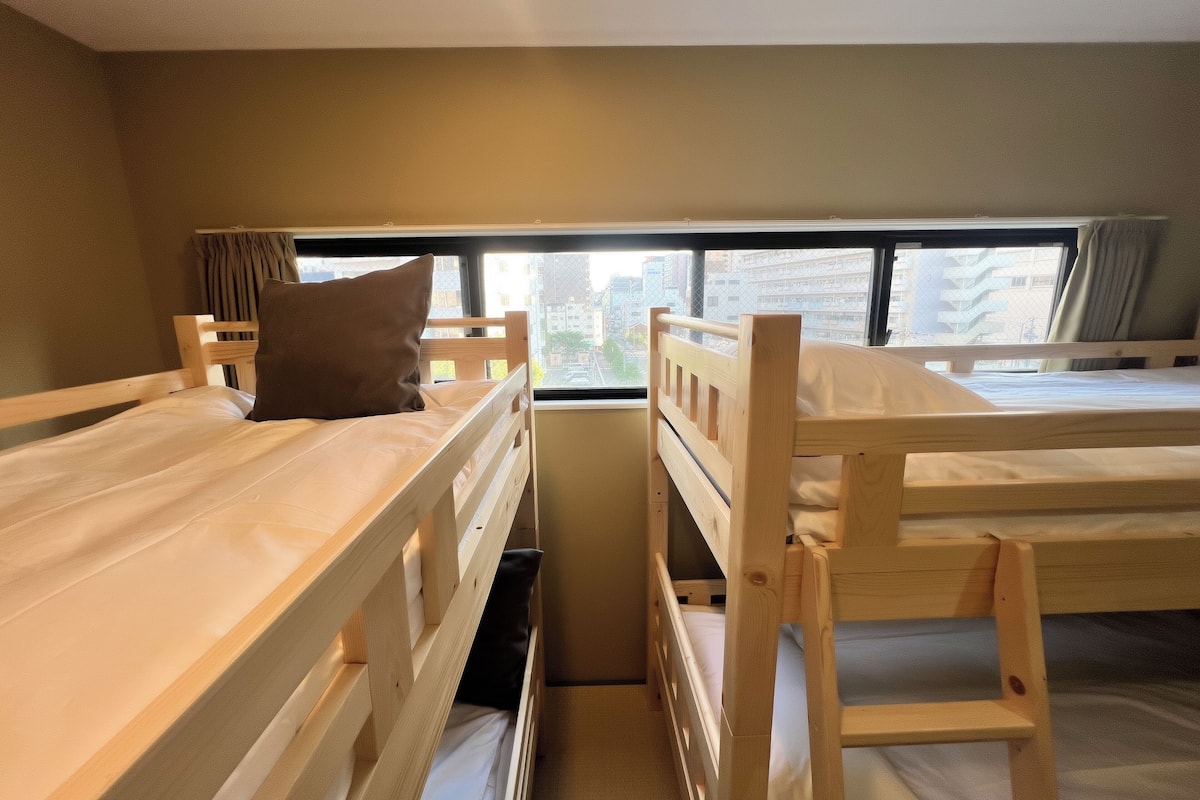 Un dormitorio con literas, una ventana con cortinas y vistas a edificios.