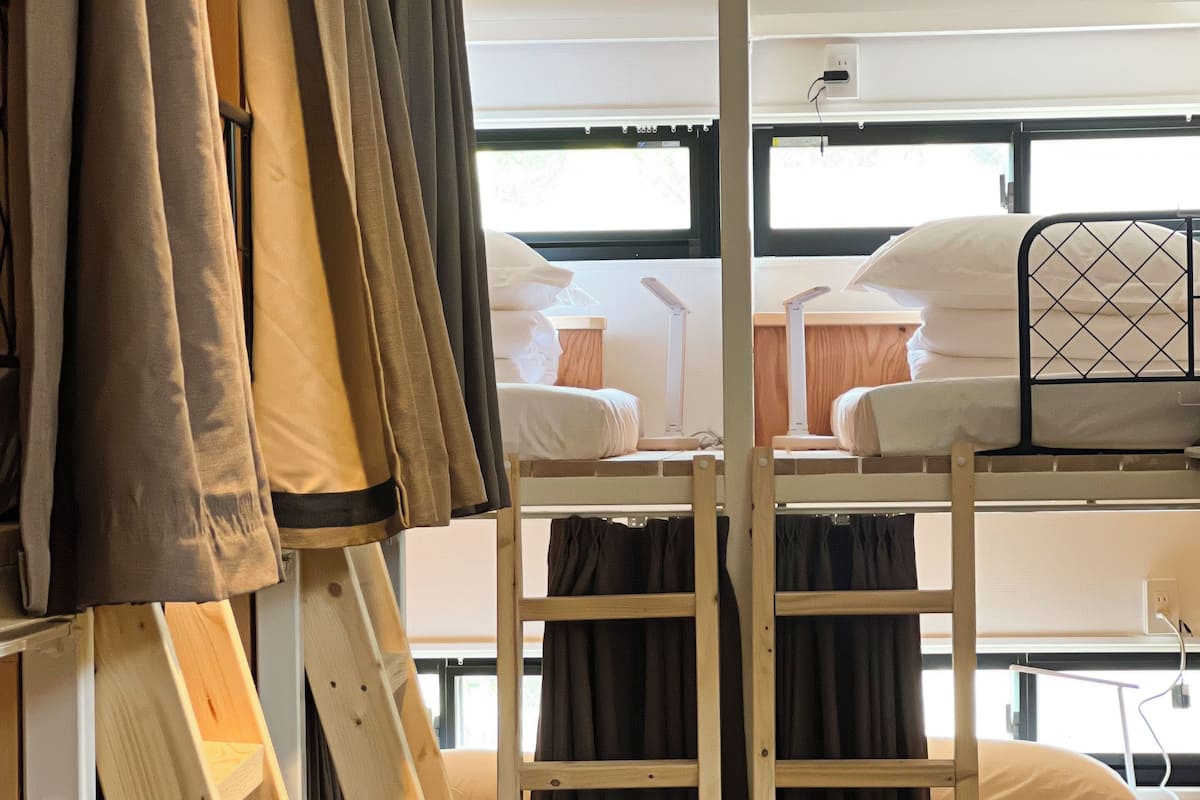 Dormitorio con literas de madera, un escritorio y una ventana con cortinas.