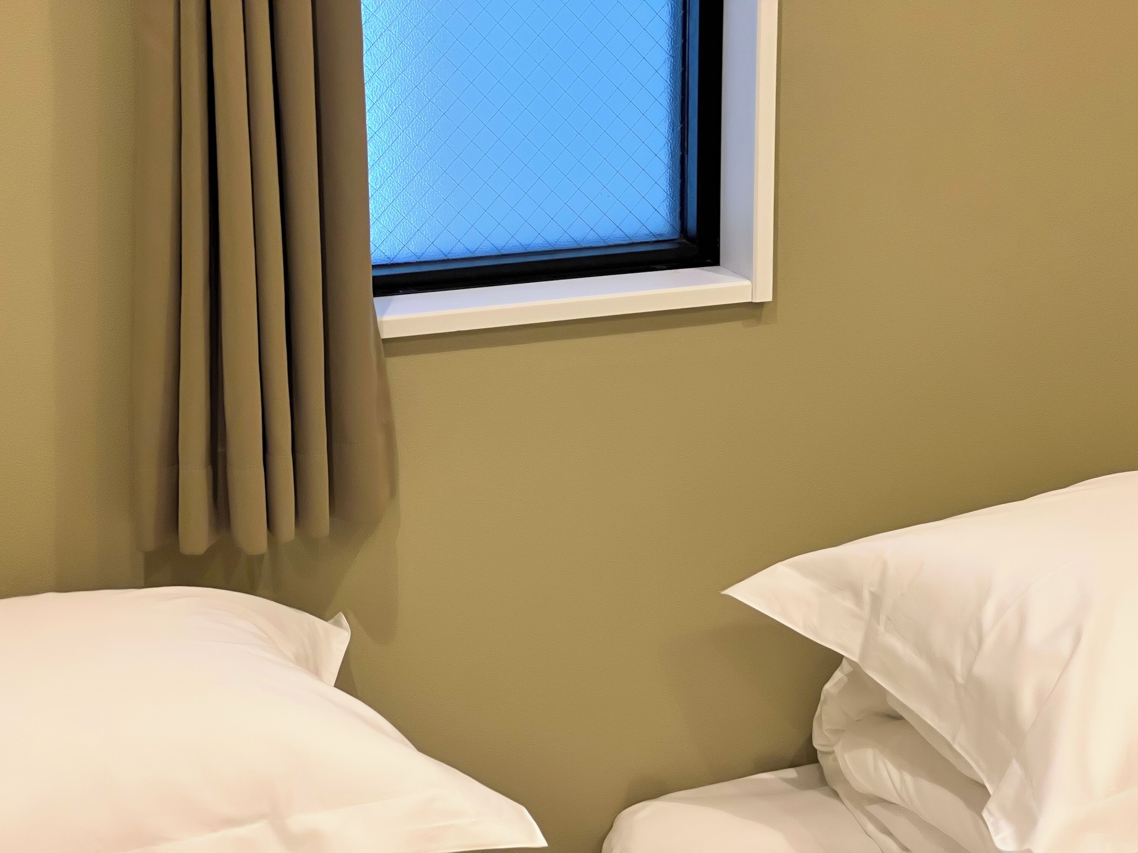 A room with a window, curtains, and two beds.