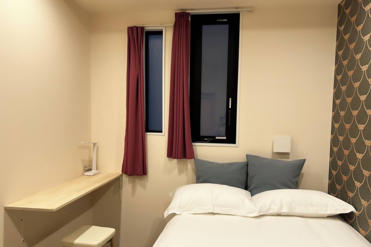 Un dormitorio pequeño y ordenado con una cama individual, un escritorio y una silla.