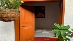 Ein Zimmer mit einem Bett, einem Fenster mit geöffnetem Durchgang und einer hängenden Pflanze.