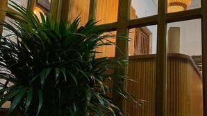 Ein Blumentopf vor einem Fenster mit Holzgeländer und einer Pendelleuchte.