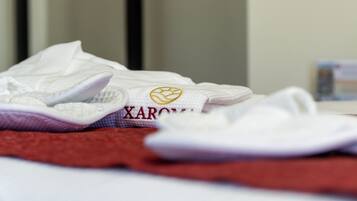 A neatly folded white towel with embroidered text and a logo on a bed.