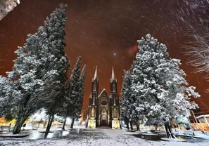 A snow-covered church with a gothic architectural style, surrounded by snow-laden trees. - Hotel Pedra Moura (Vacaria)