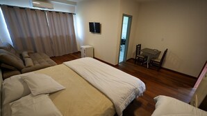 A hotel room with a large bed, a sofa, a small table, and a television.