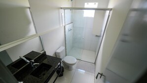 A compact bathroom with a shower, toilet, and sink.
