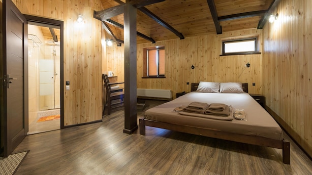 Quarto com painéis de madeira, uma cama, uma escrivaninha e uma janela.
