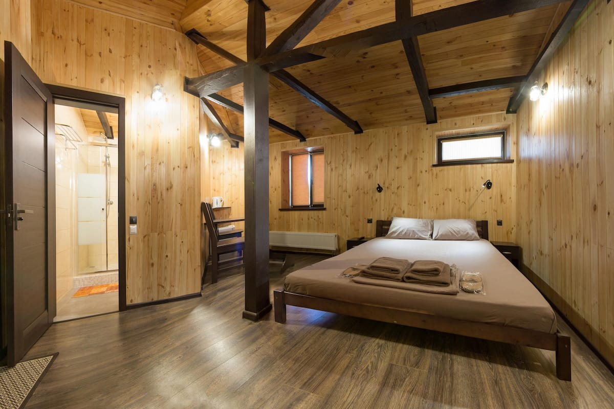Ein Zimmer mit Holzwandverkleidung, einem Bett, einem Schreibtisch und einem Fenster.