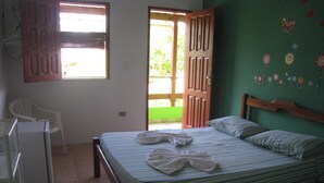 Un dormitorio con una cama, una silla, una mesita y una puerta que da a un espacio exterior.