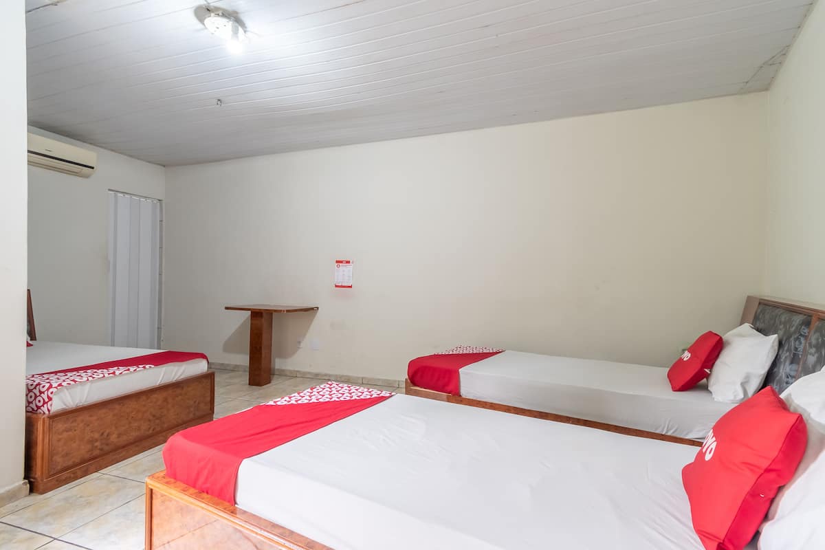 Een hotelkamer met twee eenpersoonsbedden, een houten hoofdbord, een klein houten tafeltje en een wit plafond.