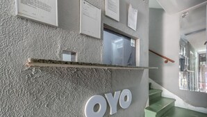 Pared con textura, un letrero que dice “OYO” y una baranda de madera.