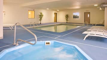 An indoor swimming pool with a blue floor, a lifeguard chair, and a door marked 'EXIT'.