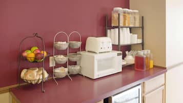 A kitchen counter with a fruit basket, a coffee maker, and storage containers.