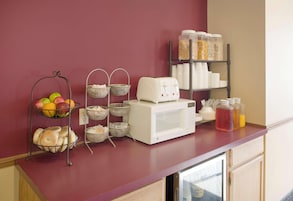 A kitchen counter with a fruit basket, a coffee maker, and storage containers.