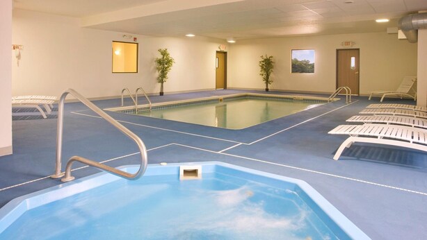 Une piscine intérieure avec un sol bleu, un poste de surveillance pour le sauveteur et une porte marquée « SORTIE ».