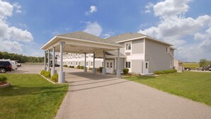 Un motel doté d’un parking couvert, d’une allée en gravier et d’une pelouse.