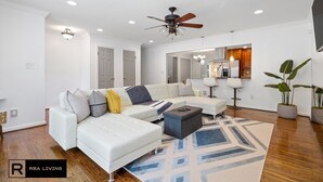 Un salon moderne avec un canapé d’angle blanc, une table basse et un tapis à motifs.