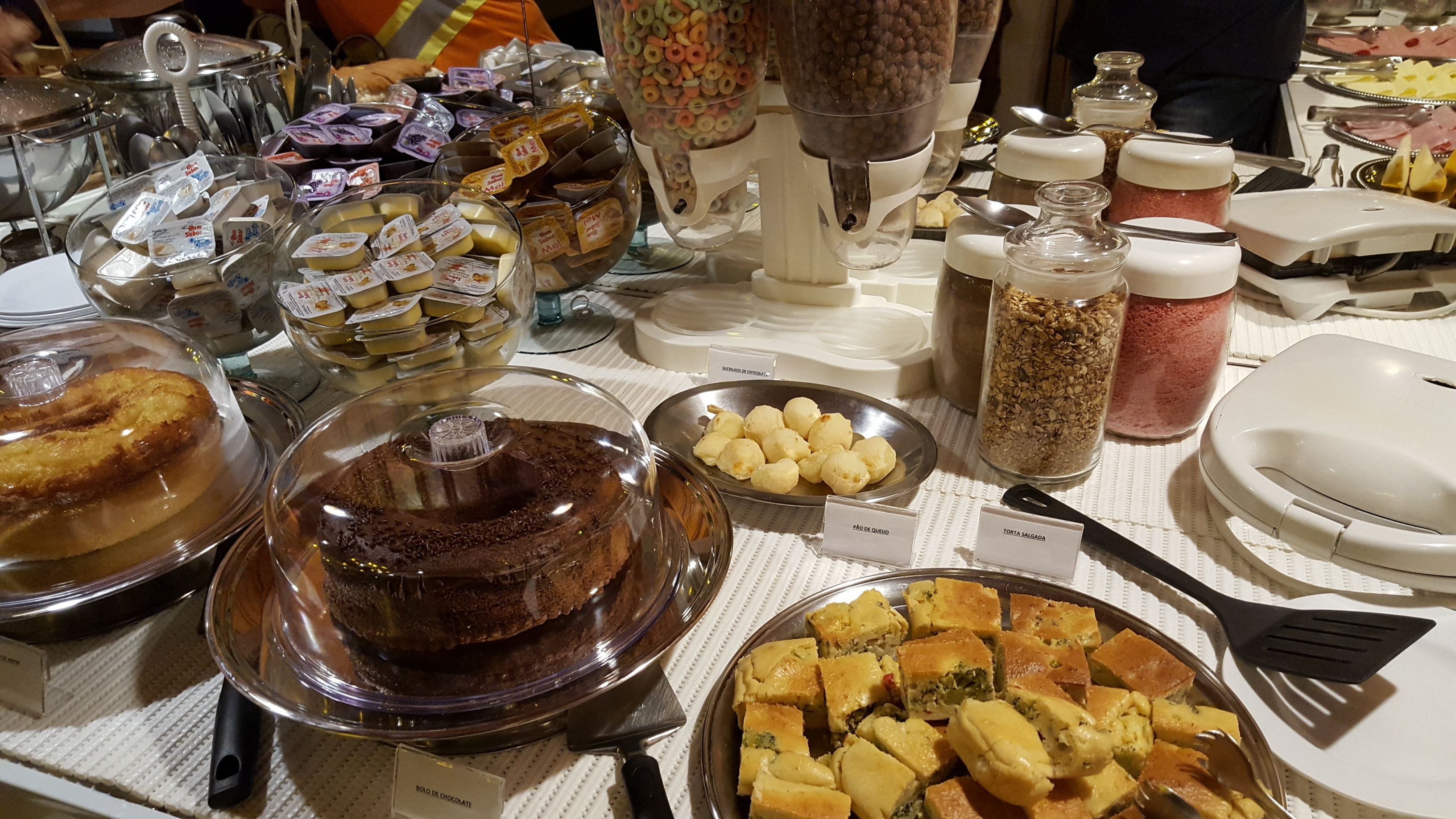 A buffet table with various food items, including cakes, pastries, and condiments.