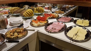 Un bufé con diversas opciones de comida, incluyendo frutas, carnes y postres.