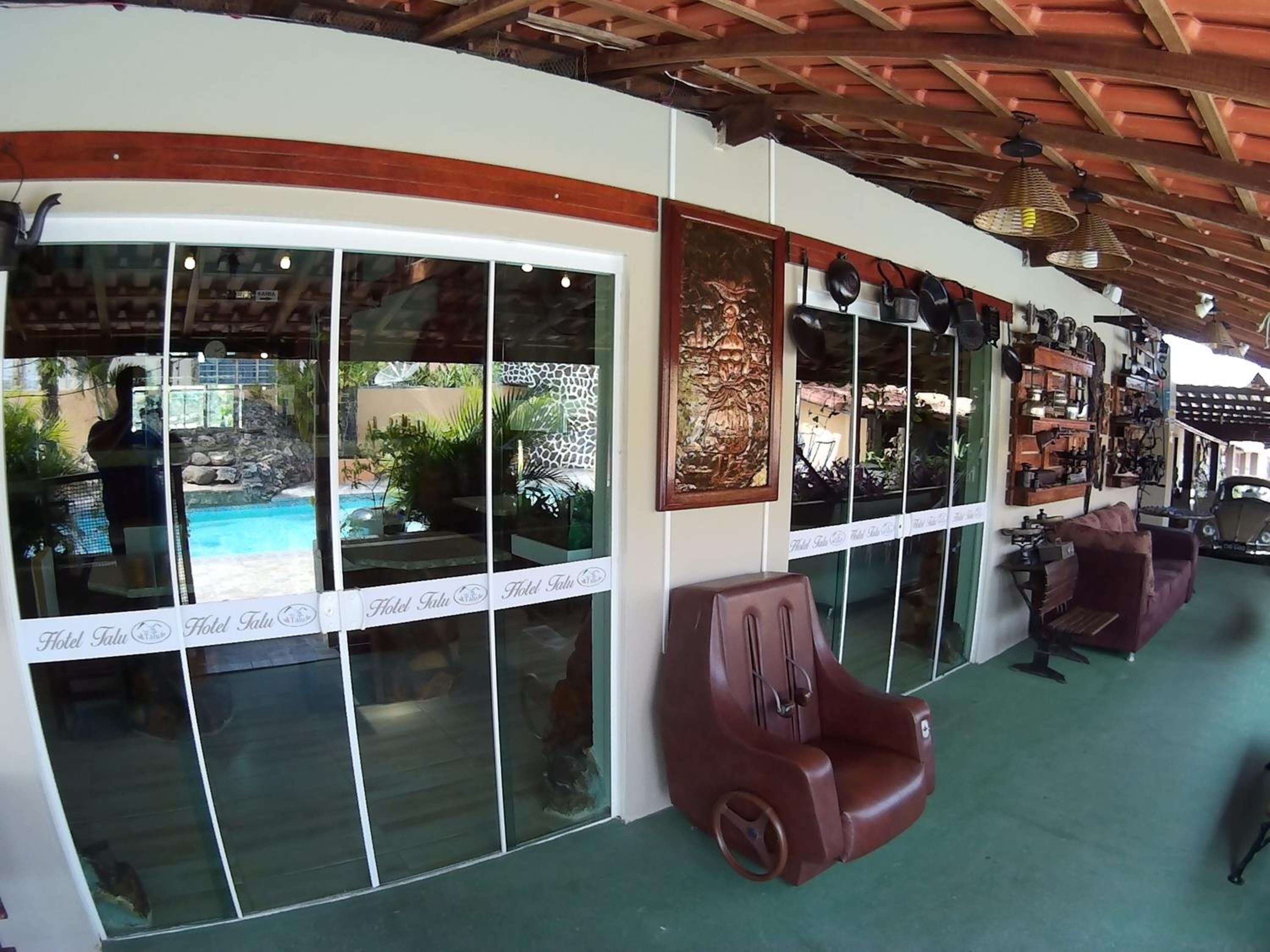 A hotel lobby with large windows, a pool view, and a seating area with a brown armchair.