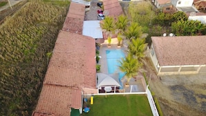 Vista aérea de una zona residencial con piscina, patio cercado y un edificio con techo de tejas rojas.
