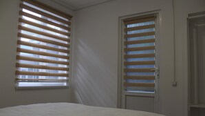 A bedroom with a bed, two windows with blinds, and a door. - Park Hostel Osh (Osh)