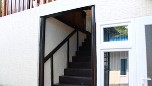 A staircase leading to a door with a glass window, white walls, and a wooden handrail. - Park Hostel Osh (Osh)