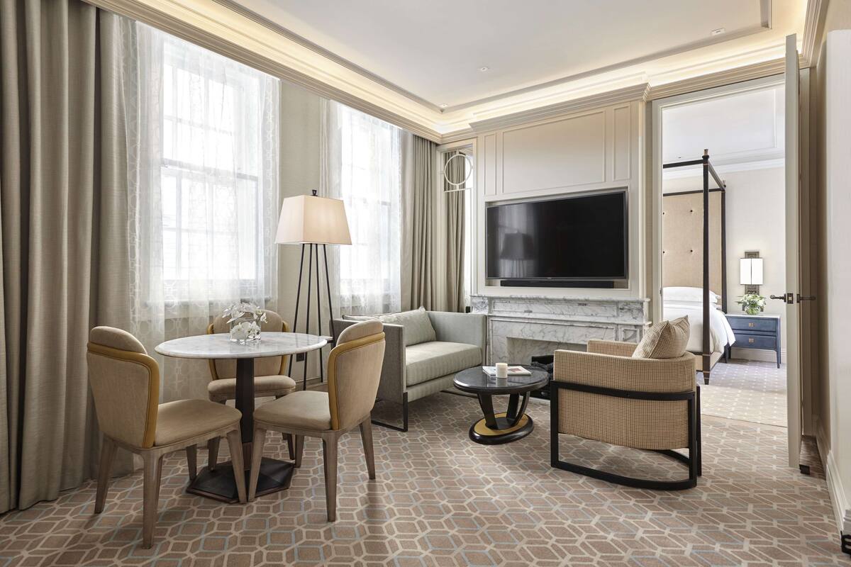 Une chambre d’hôtel équipée d’un canapé, de fauteuils, d’une télévision, d’une cheminée et d’un coin repas.