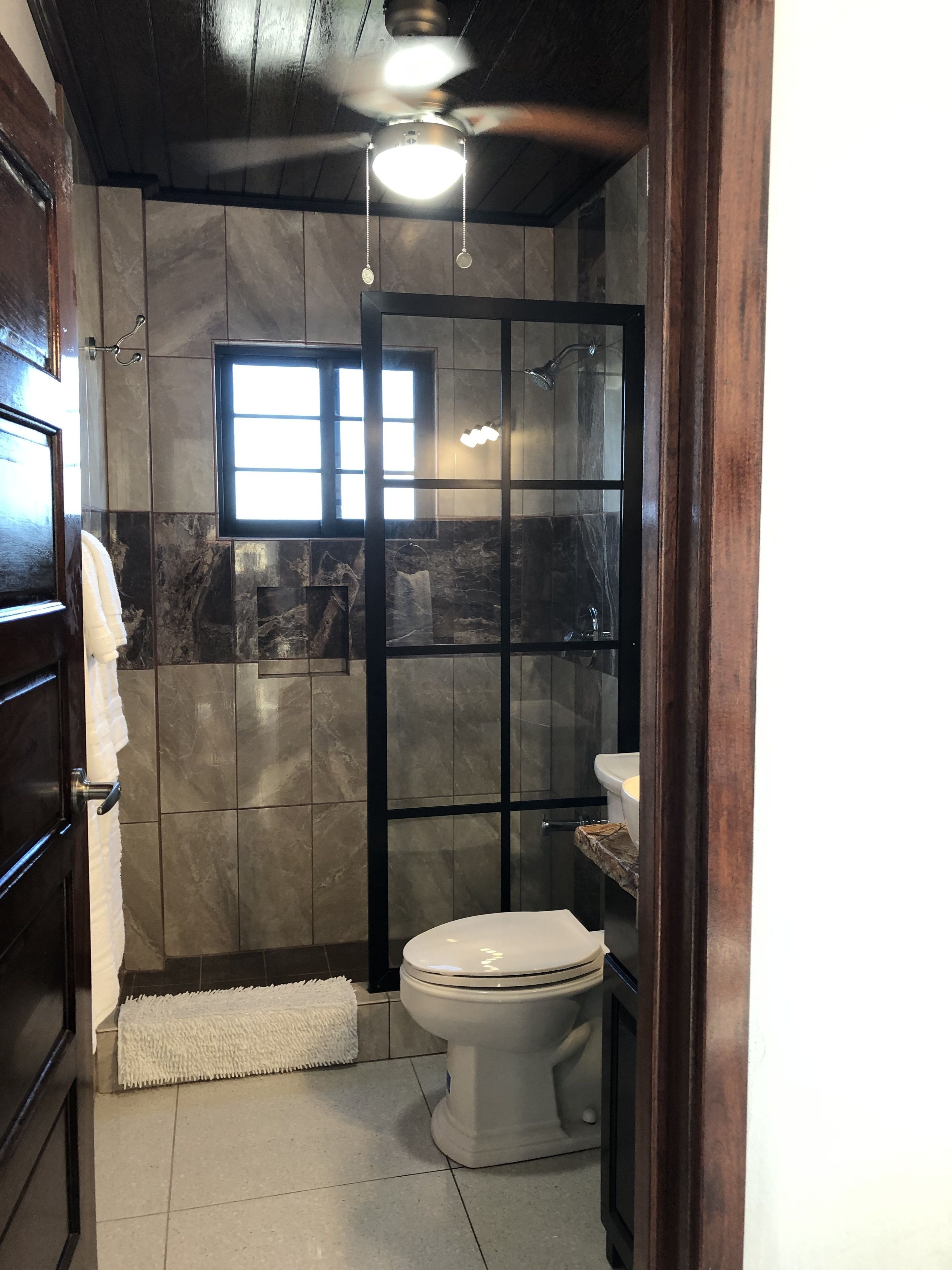 Une salle de bain avec une douche, des toilettes et une fenêtre.