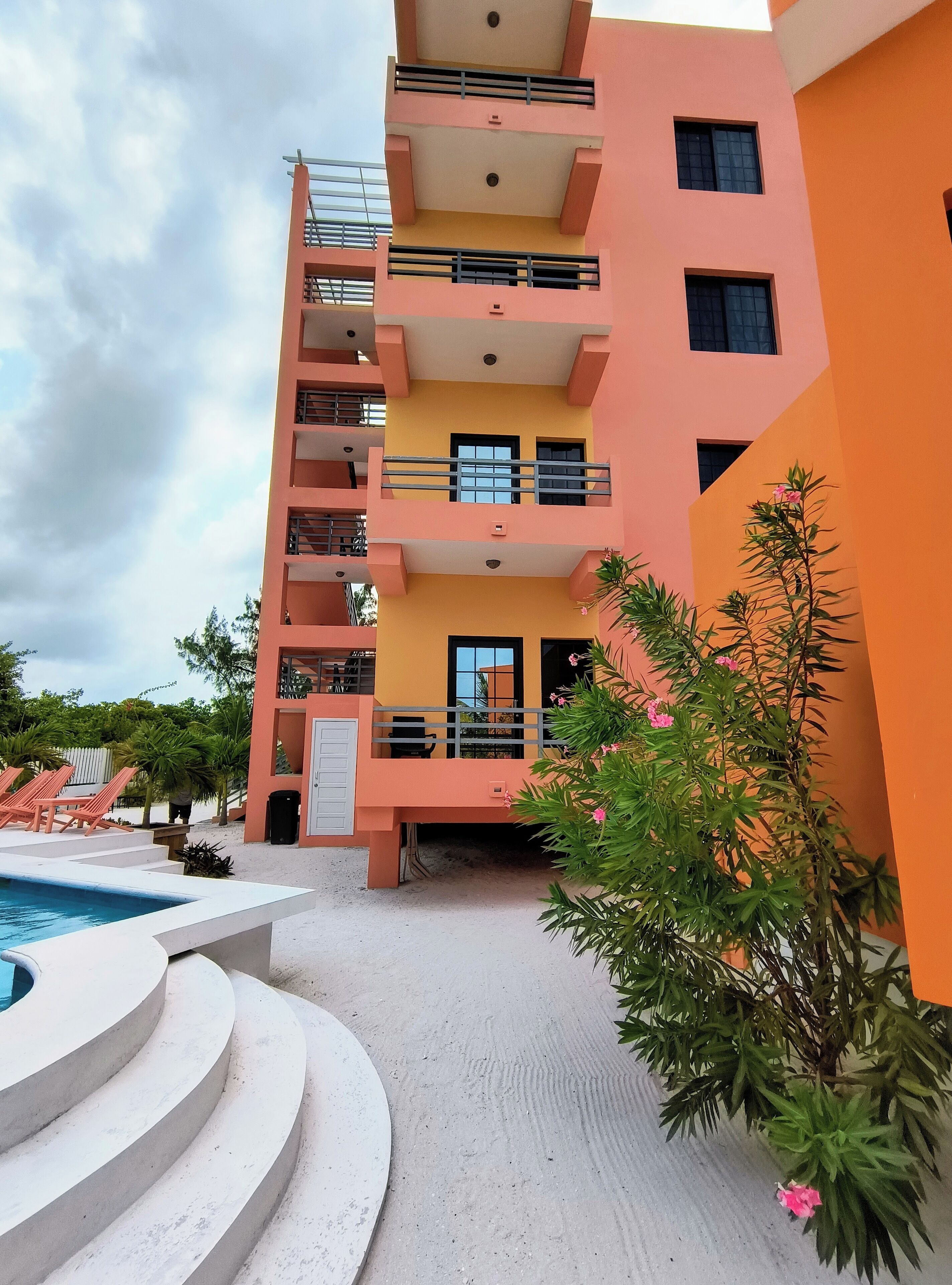 A multi-story building with balconies, a swimming pool, and a garden area.