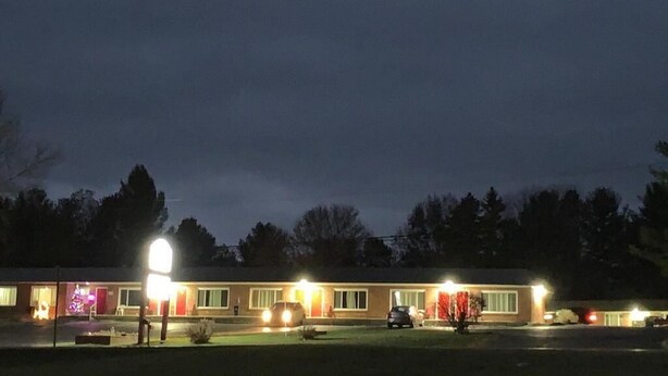 A motel with multiple rooms, a parking lot, and a well-lit exterior. - Baw Beese Inn (Hillsdale)