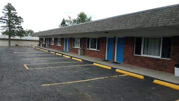 A motel with a row of rooms, a parking lot, and a brick facade.