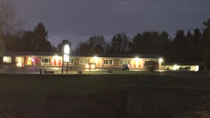 A motel with multiple rooms, a parking area, and a well-lit exterior. - Baw Beese Inn (Hillsdale)