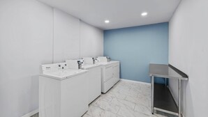 A laundry room with a Whirlpool washer and dryer, a sink, and a small table.