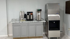 A kitchenette with a coffee machine, a water dispenser, and stacked cups.