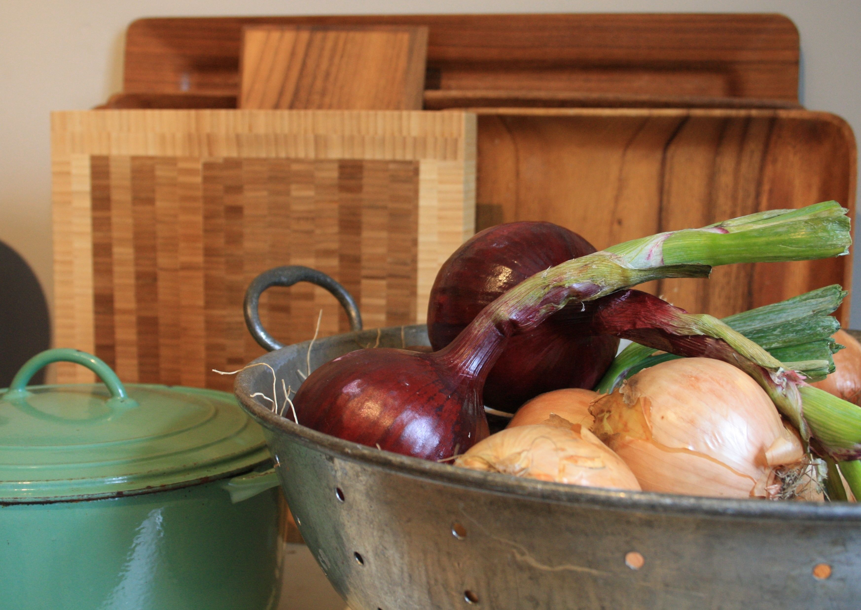 A metal colander with onions and leeks.