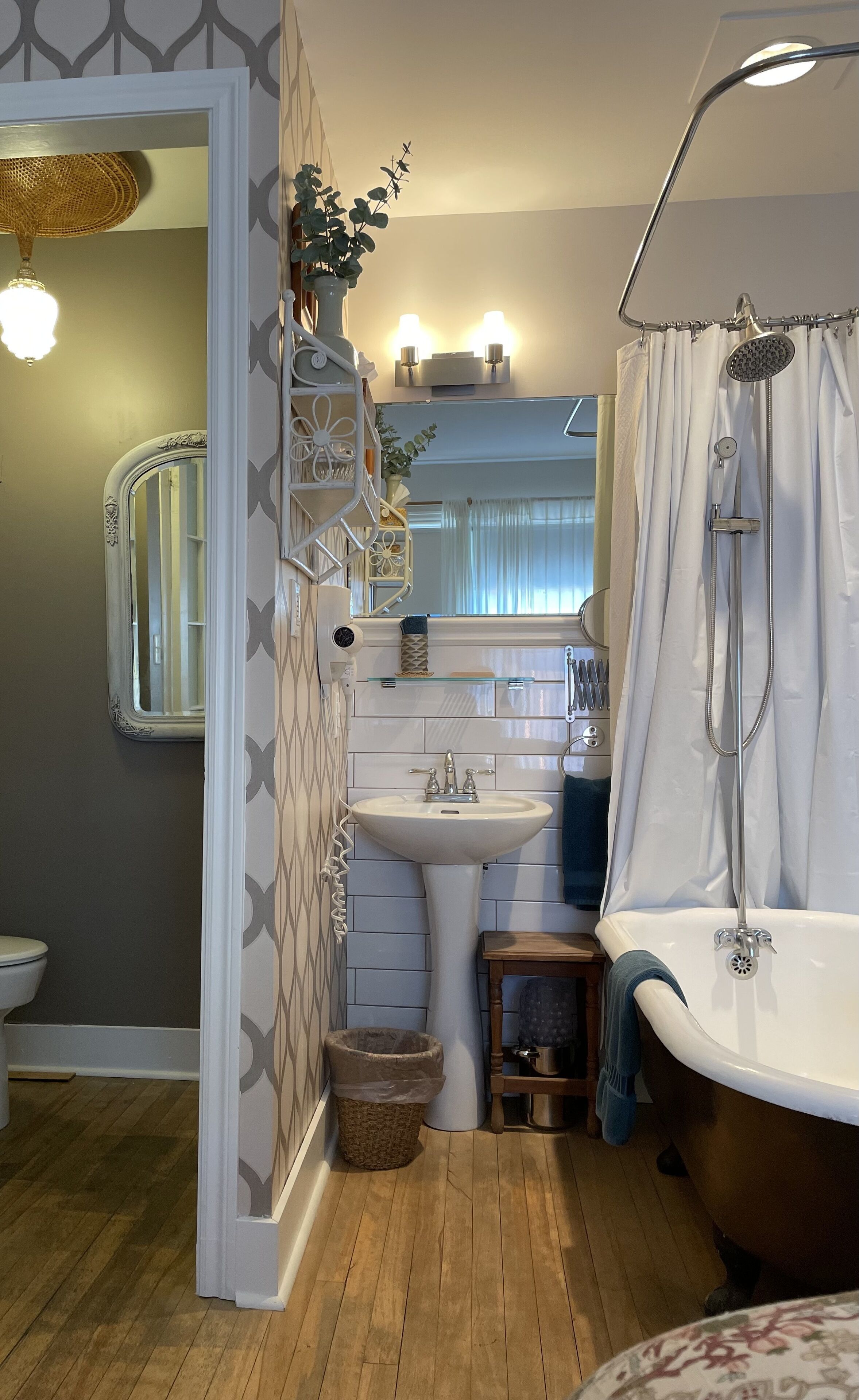 Een badkamer met een vrijstaand bad, een wastafel, een spiegel en een douchegordijn.