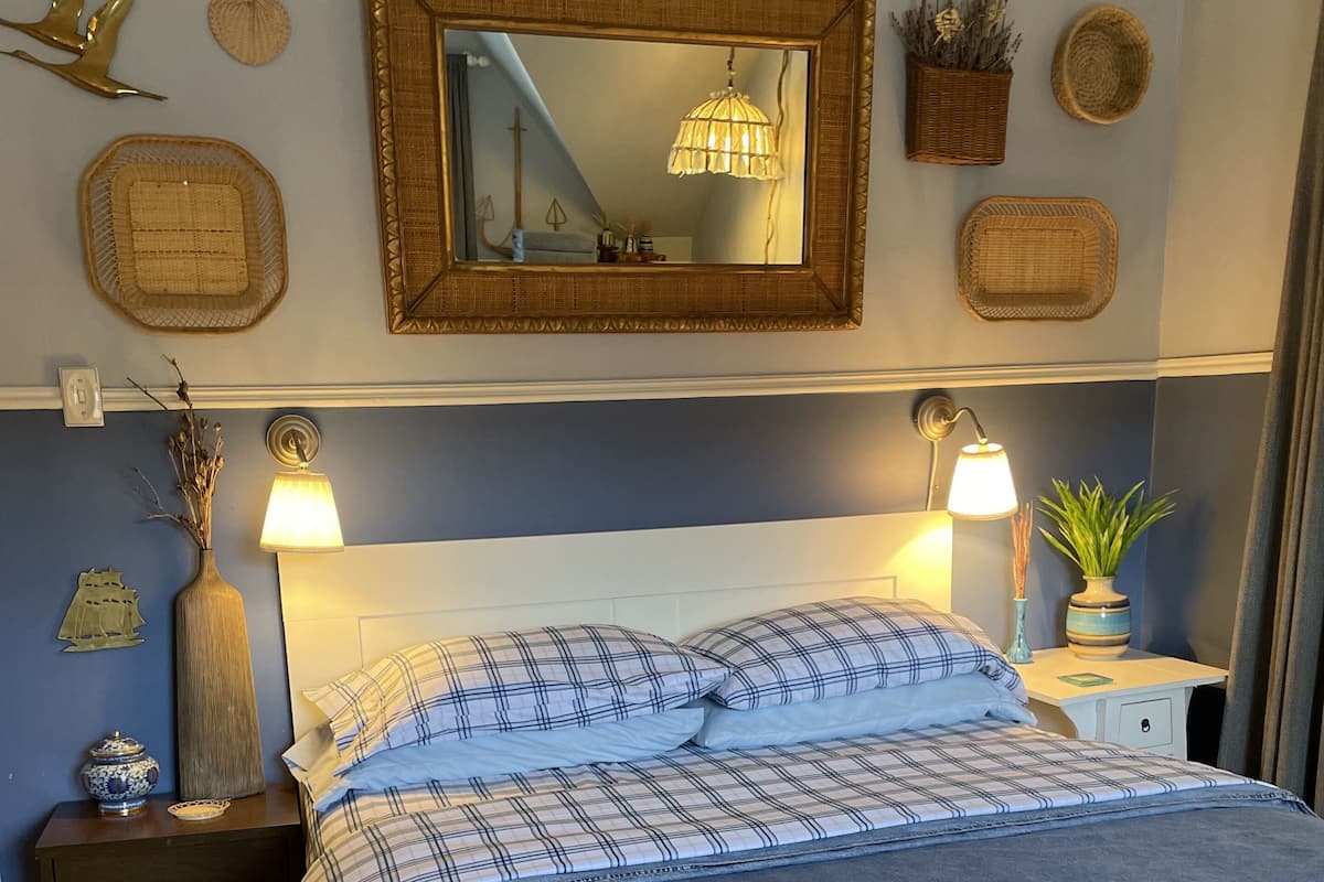 Een slaapkamer met een bed, nachtkastjes, wanddecoratie en een spiegel.