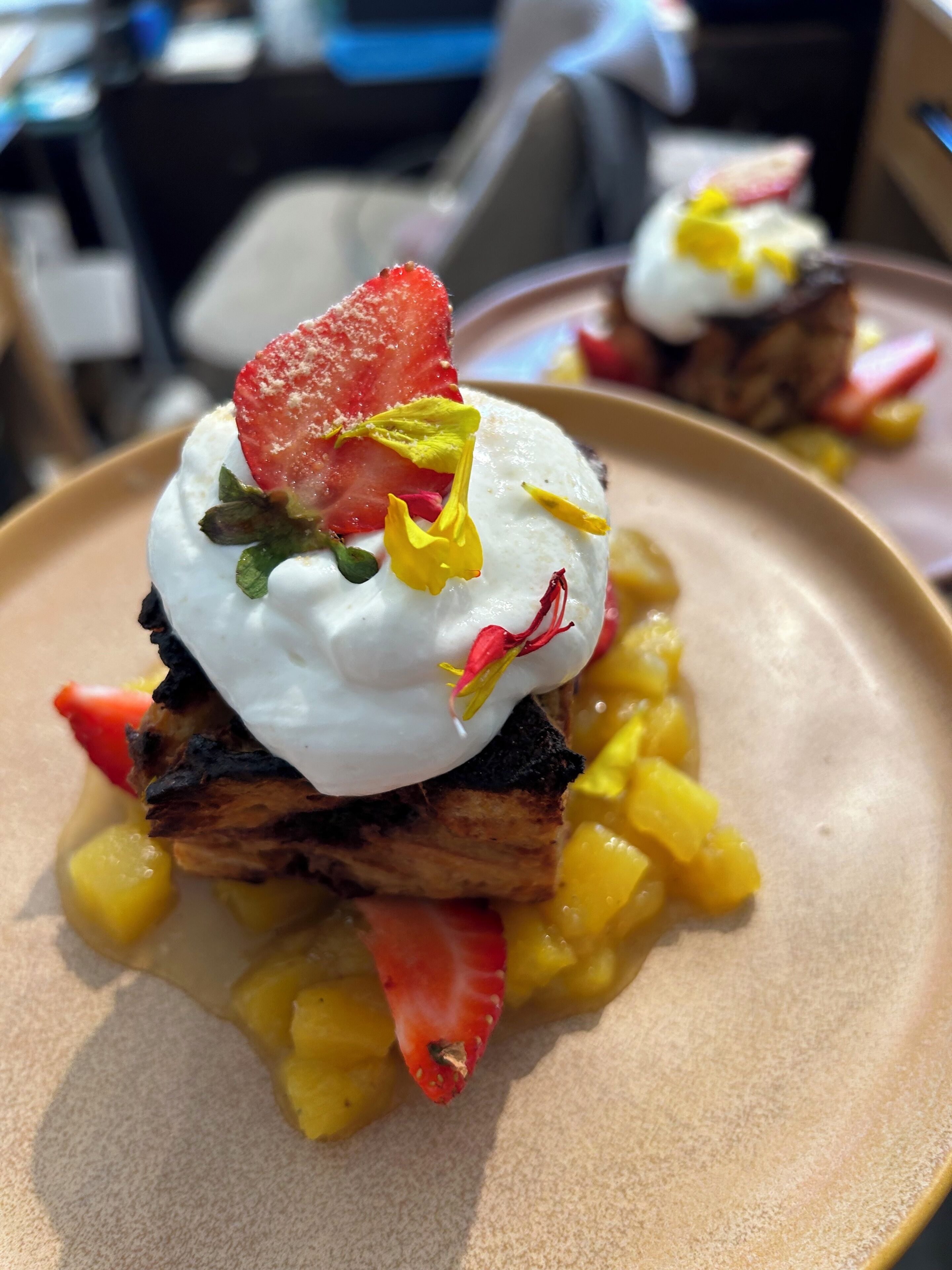 Un postre con un huevo pochado, fresas y mango en un plato.