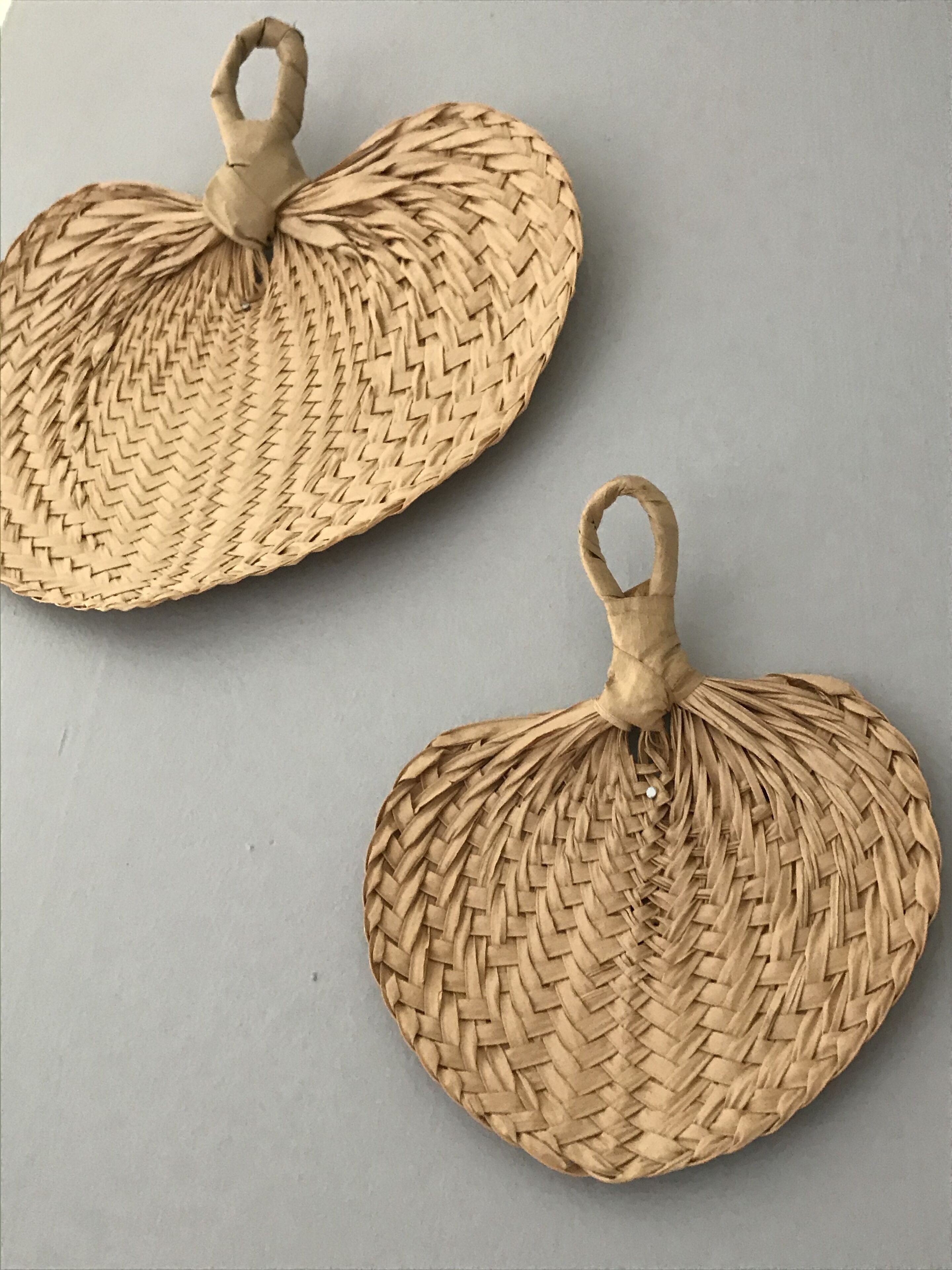 Two woven, circular objects with handles, likely serving as decorative items or small furniture pieces.