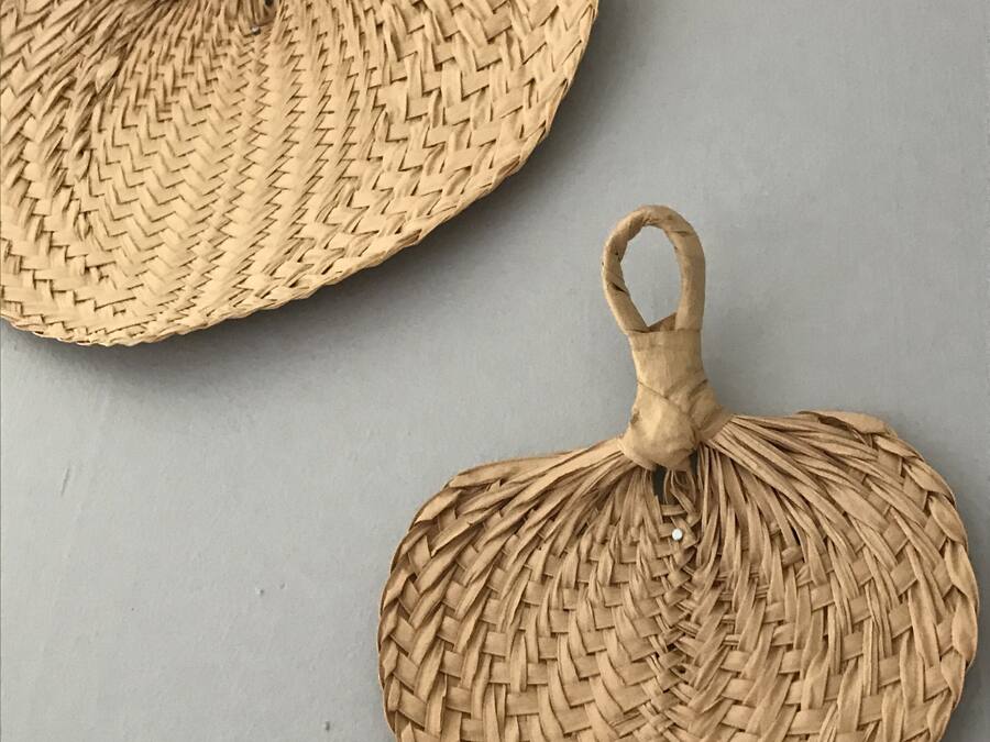 Two woven, circular objects with handles, likely serving as decorative items or small furniture pieces.