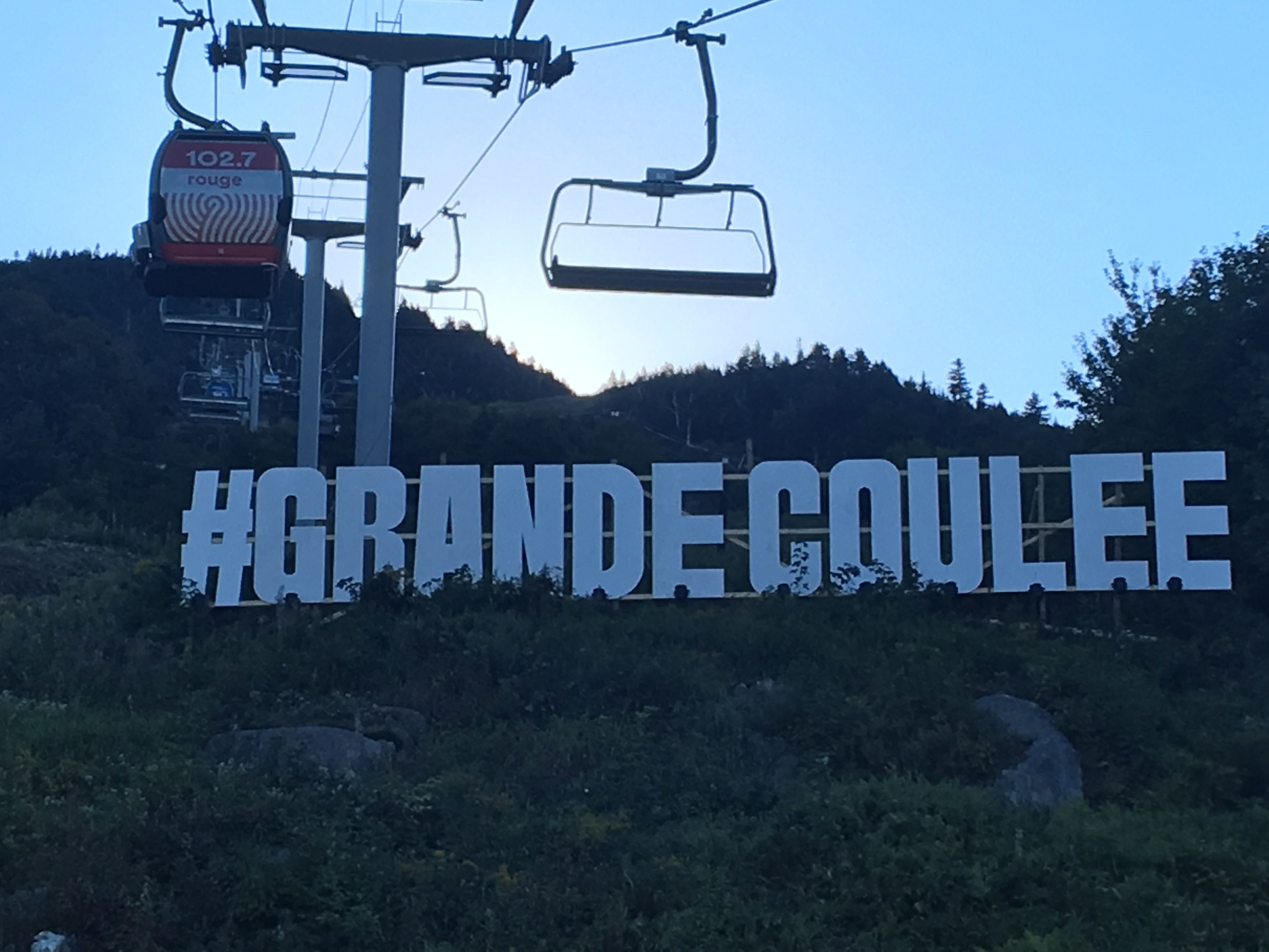A sign with the text "#GRANDECOULEE" and a ski lift in the background.